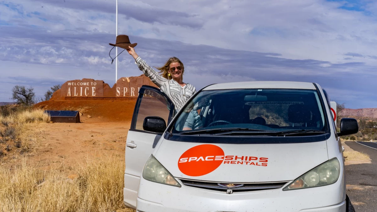 Happy Space Traveller next to their Spaceships campervan in a remote location in Australia