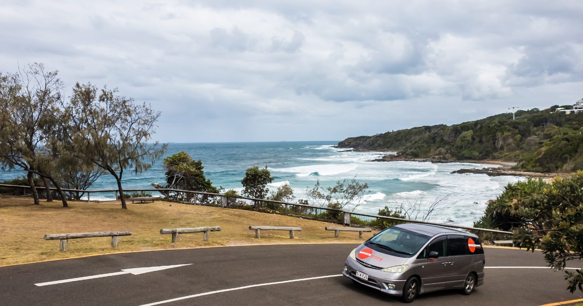 Campervan driving on a coastal road with the ocean in the background