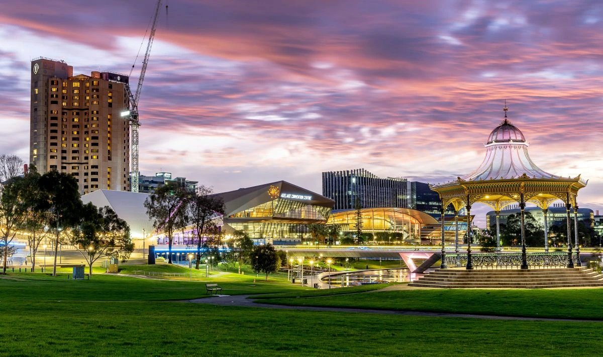 Evening view of a city from the park with a gazebo in the foreground and highrises in the background each with their lights on
