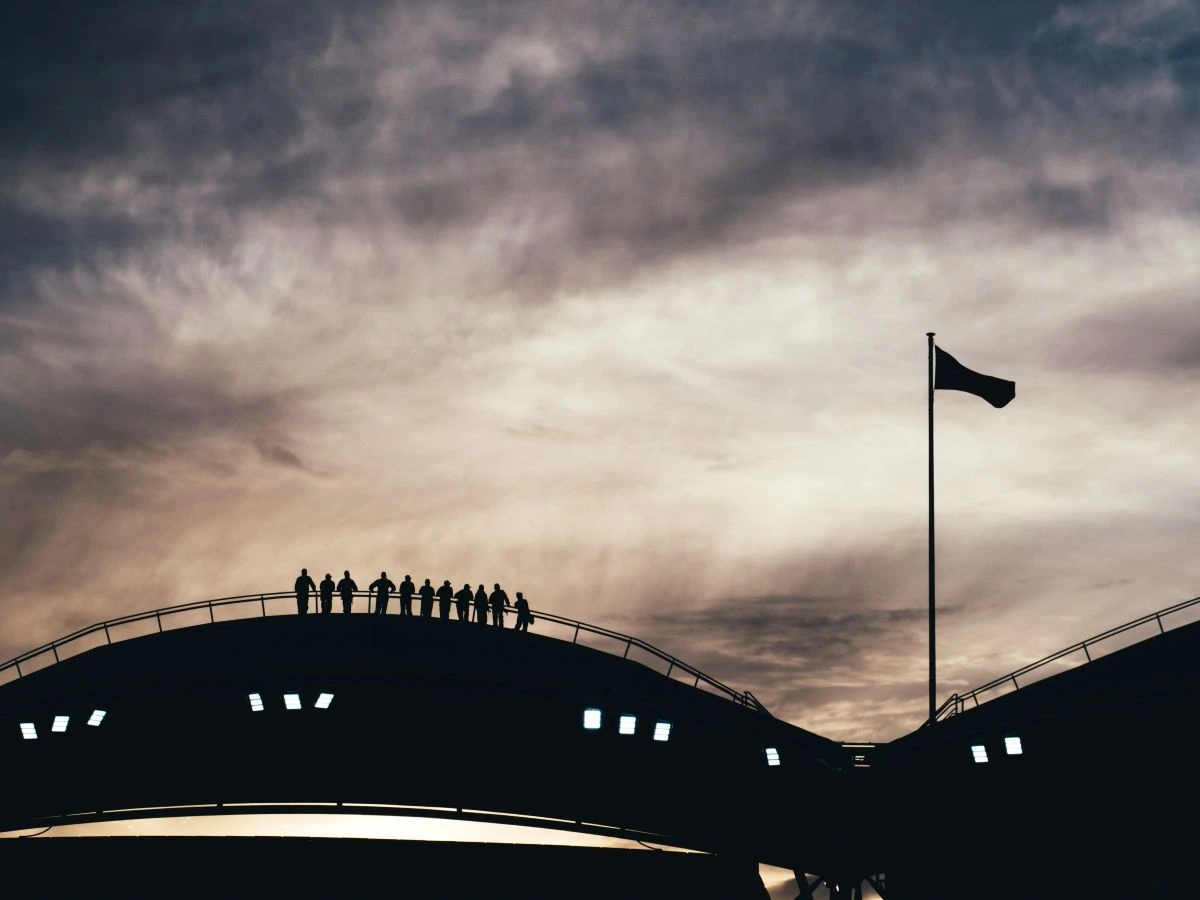 roof section of a stadium silhoutted in the sunset sky with people standing on top of the roof