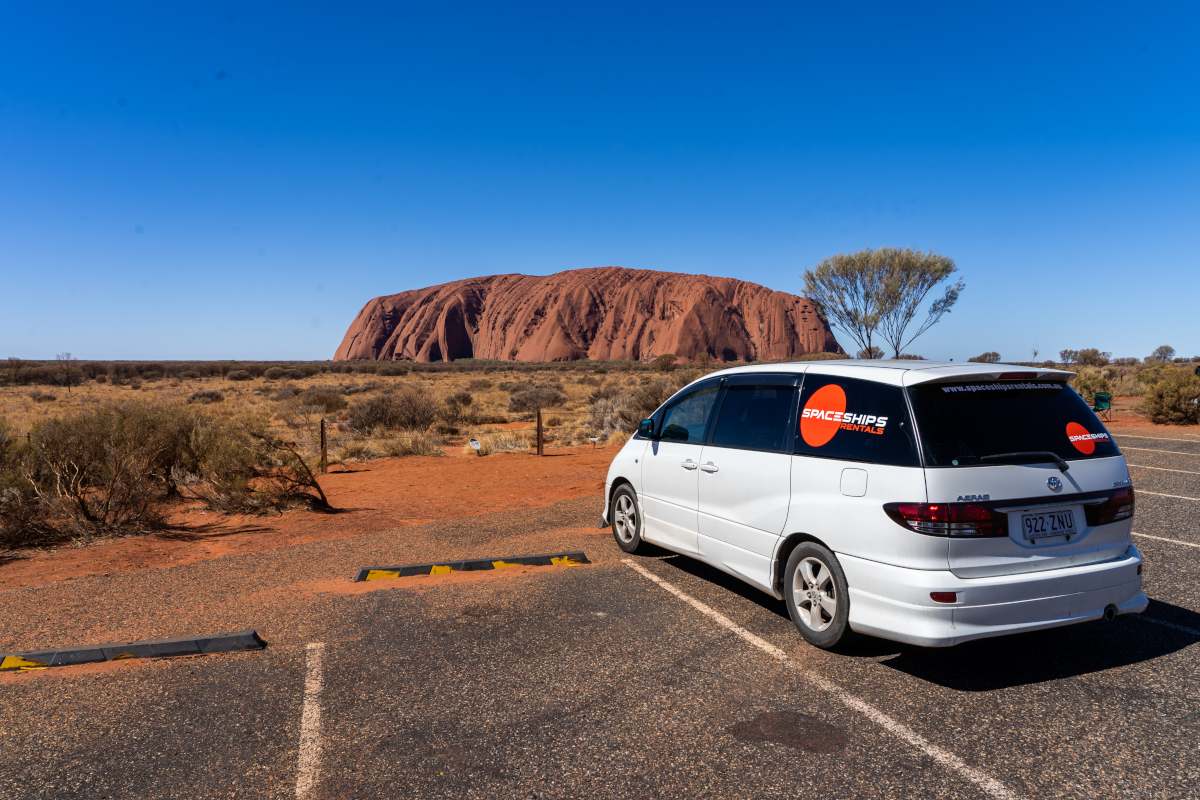 White campervan parked in front of Uluru