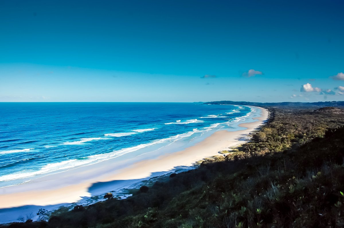 White sand beach stretching to the right with wavy blue water