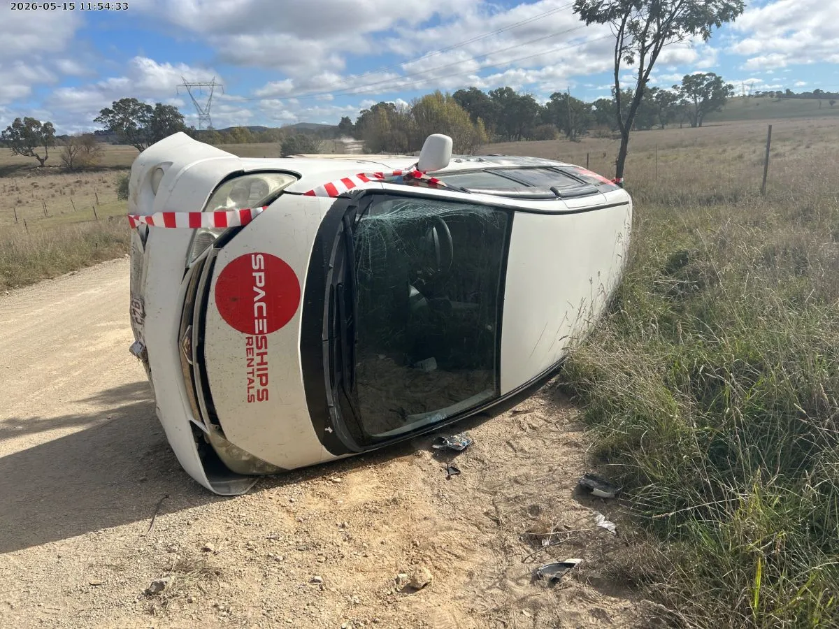 White campervan laying on its side on a rural gravel road