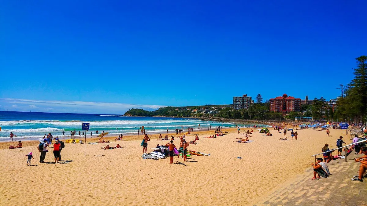 People sitting, swimming and walking on a golden sand beach