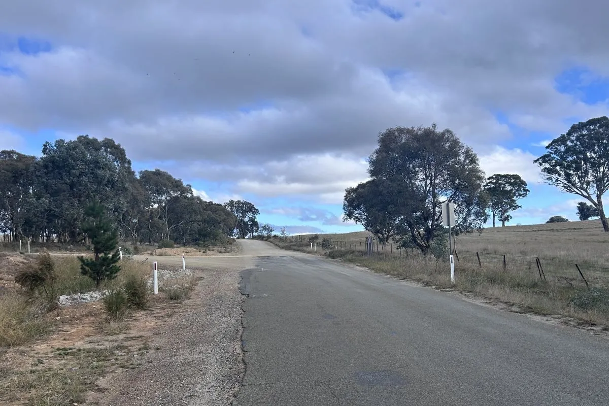 rural country road leading towards an intersection where the road turns to gravel